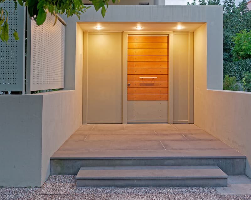 A sleek and modern front door with warm overhead lighting.