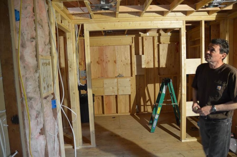 Carpenter looking at wood studs and insulation