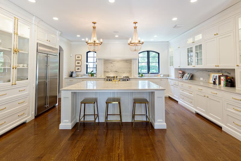 Classic chandeliers light up a bright white kitchen and gives it a soft glow for warmth