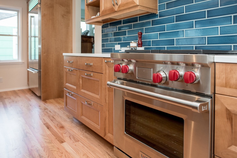 Wolf range with red handles and blue tile backsplash