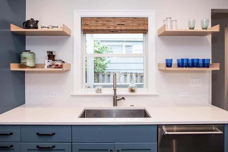 Small kitchen with blue cabinets, white quartz countertops, and styled open shelving